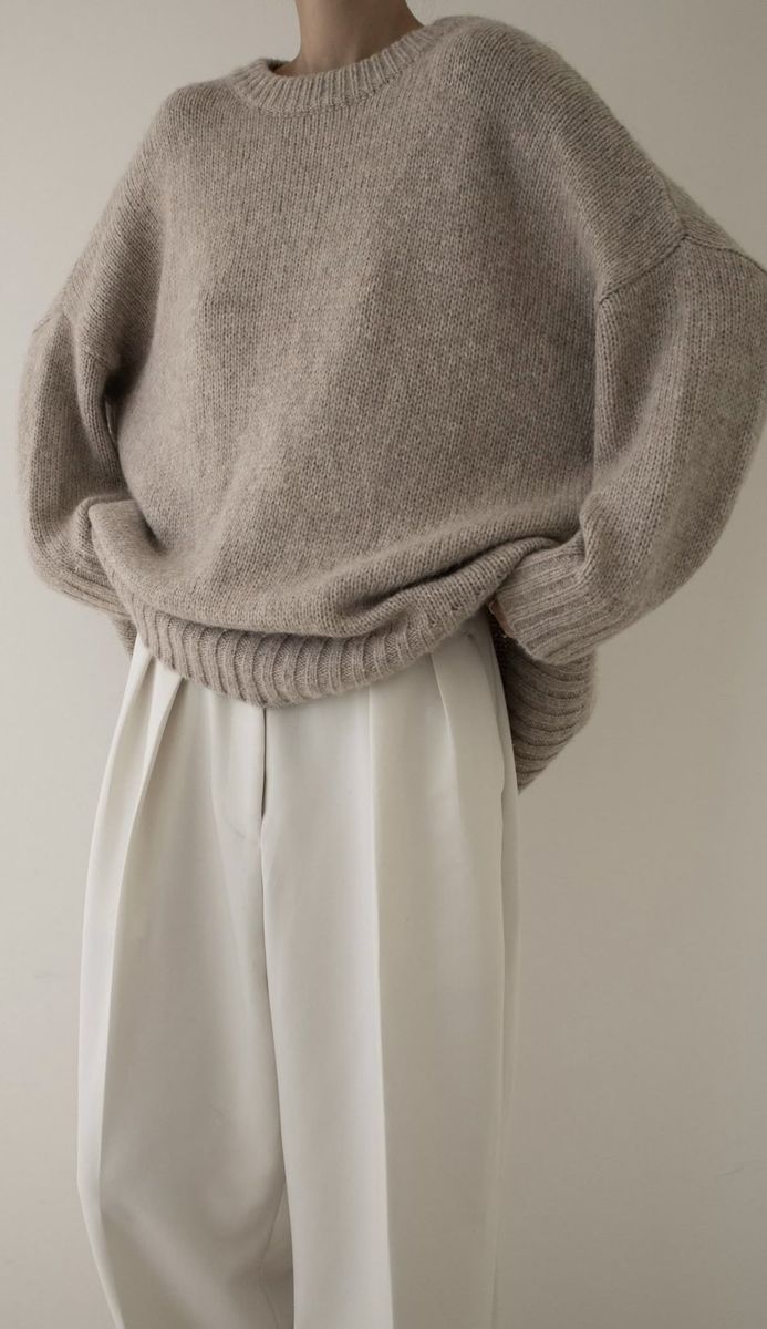 Oversized grey knit sweater with white pleated trousers, cropped at the shoulders