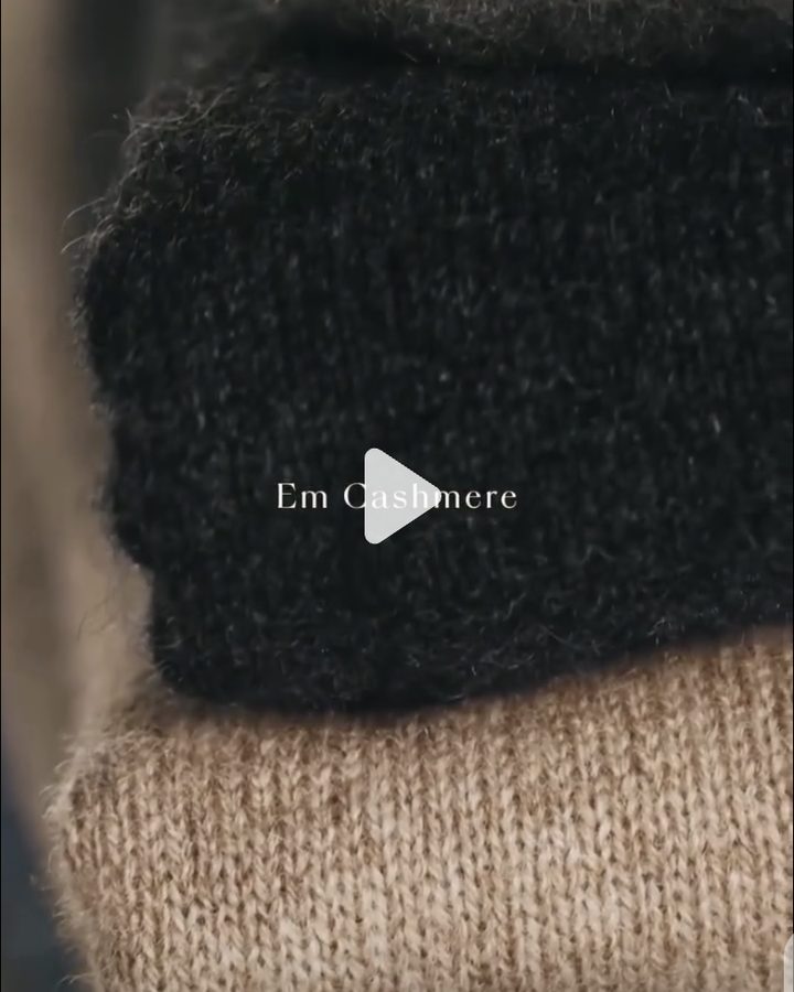 Stack of folded charcoal and camel cashmere knits, close up